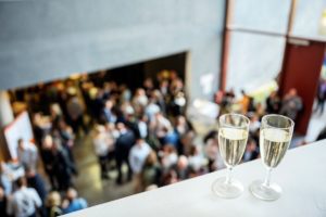 2 champagne glasses in focus on balcony above large corporate event