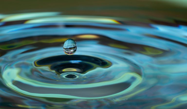 water drop falling and impacting on a body of water close up