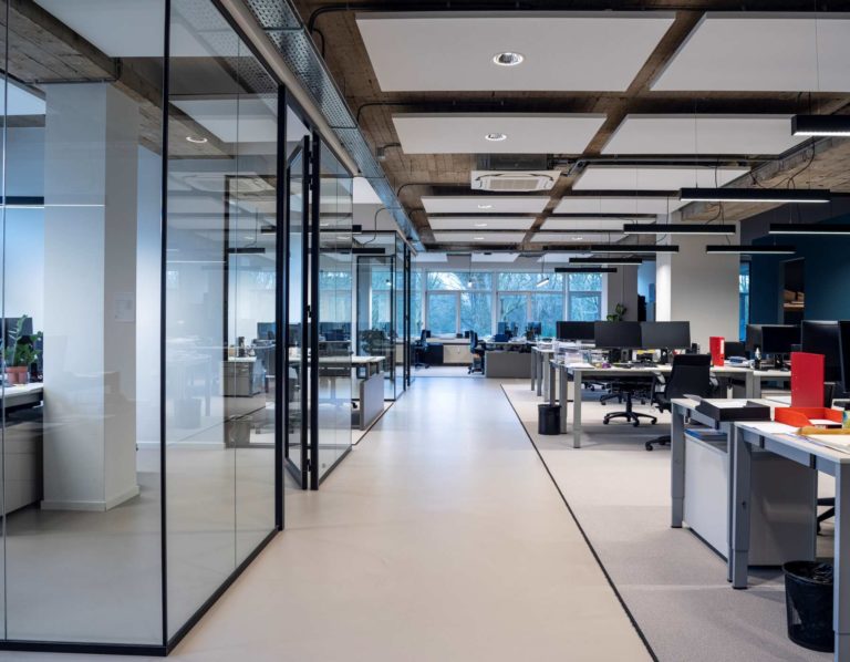 large, empty, open plan modern office space with large glass walls, hard flooring and carpet
